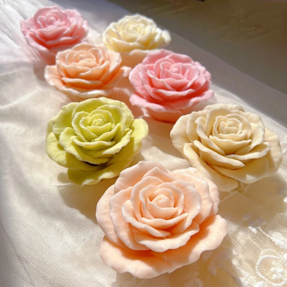 Six open rose candle castings on a fabric surface