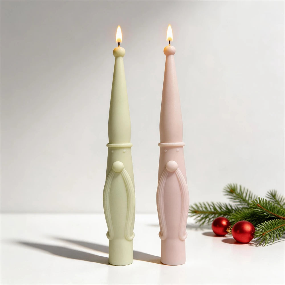 Two lit long-beard Santa taper candles beside a small holiday tree