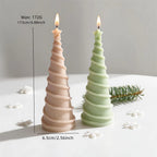 Two spiral Christmas tree candles standing in a festive arrangement