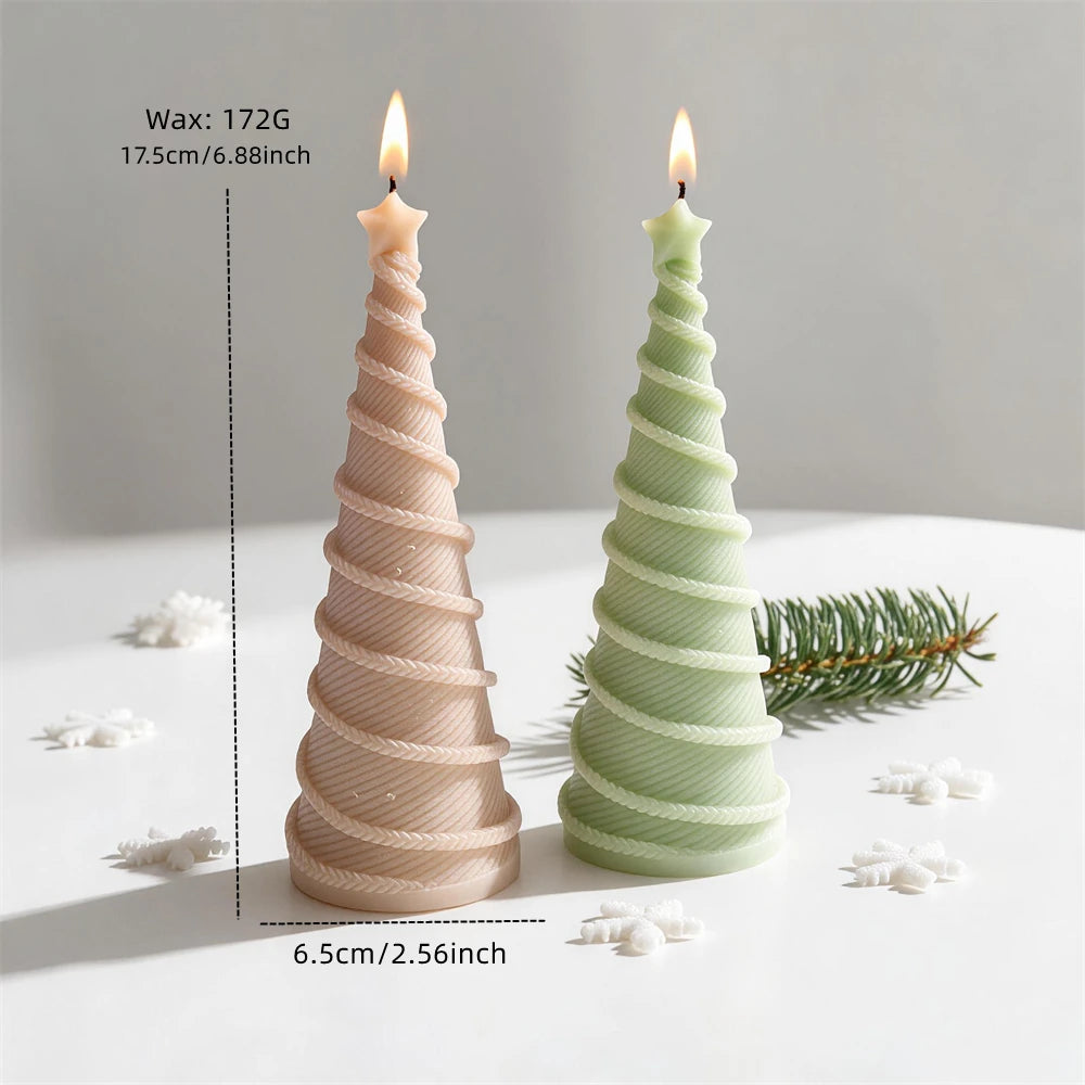 Two spiral Christmas tree candles standing in a festive arrangement