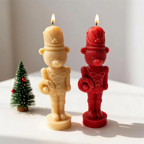Cream and red bear nutcracker candles beside a miniature Christmas tree