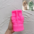 Pink silicone cottage mitten mold held upright in a hand beside finished candles