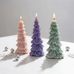 Three layered Christmas tree candles beside silver ornaments