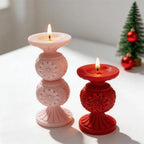 Pink double-globe and red single-globe snowflake candles beside a miniature Christmas tree