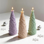 Angled star topped fir tree candles beside festive ornaments