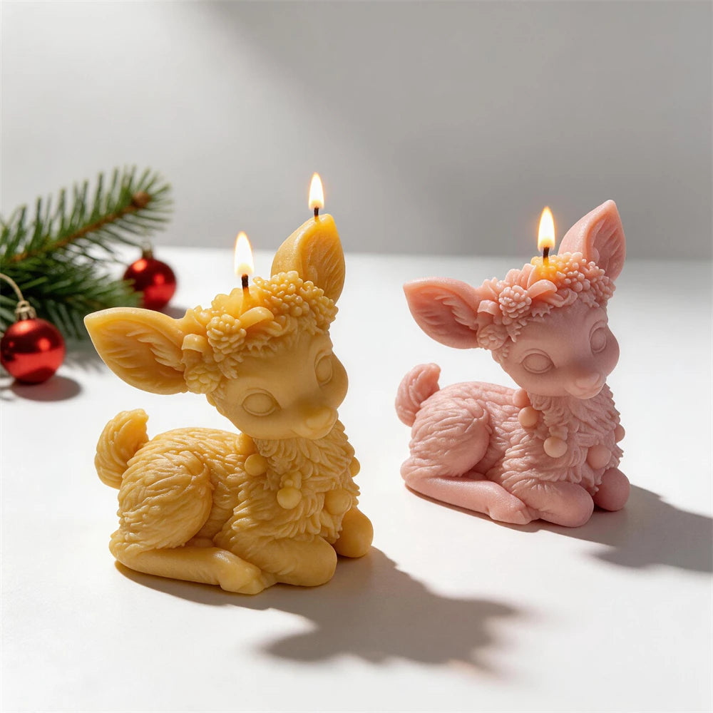 Golden and pink sculpted sitting reindeer candles beside Christmas ornaments