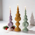 Three ornamental finial candles with stacked sections and flower medallions