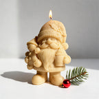 Closeup of golden Christmas gnome candle holding gingerbread and mug