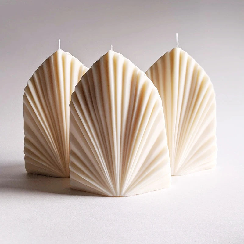 Three cream fan-ribbed upright leaf-shaped candle castings on a neutral backdrop