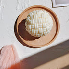 Top view of a cream woven ball casting in a round wooden tray