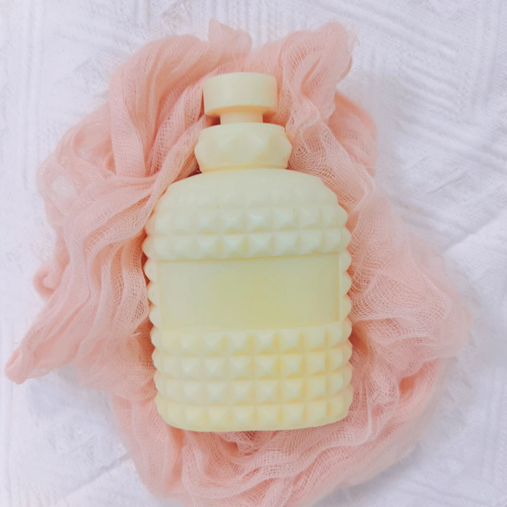 Cream perfume bottle-shaped casting on pink fabric with faceted stud bands