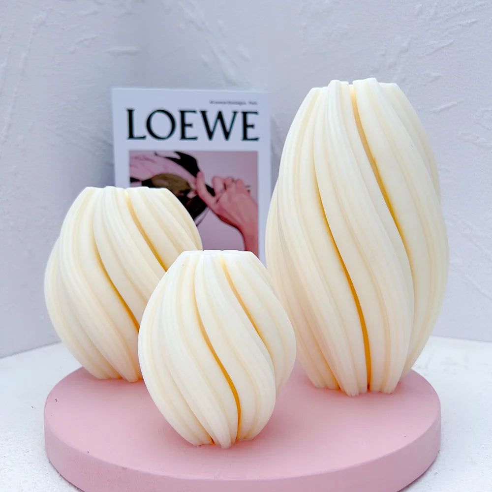 Spiral-rib oval figures in three sizes displayed on a pink round stand