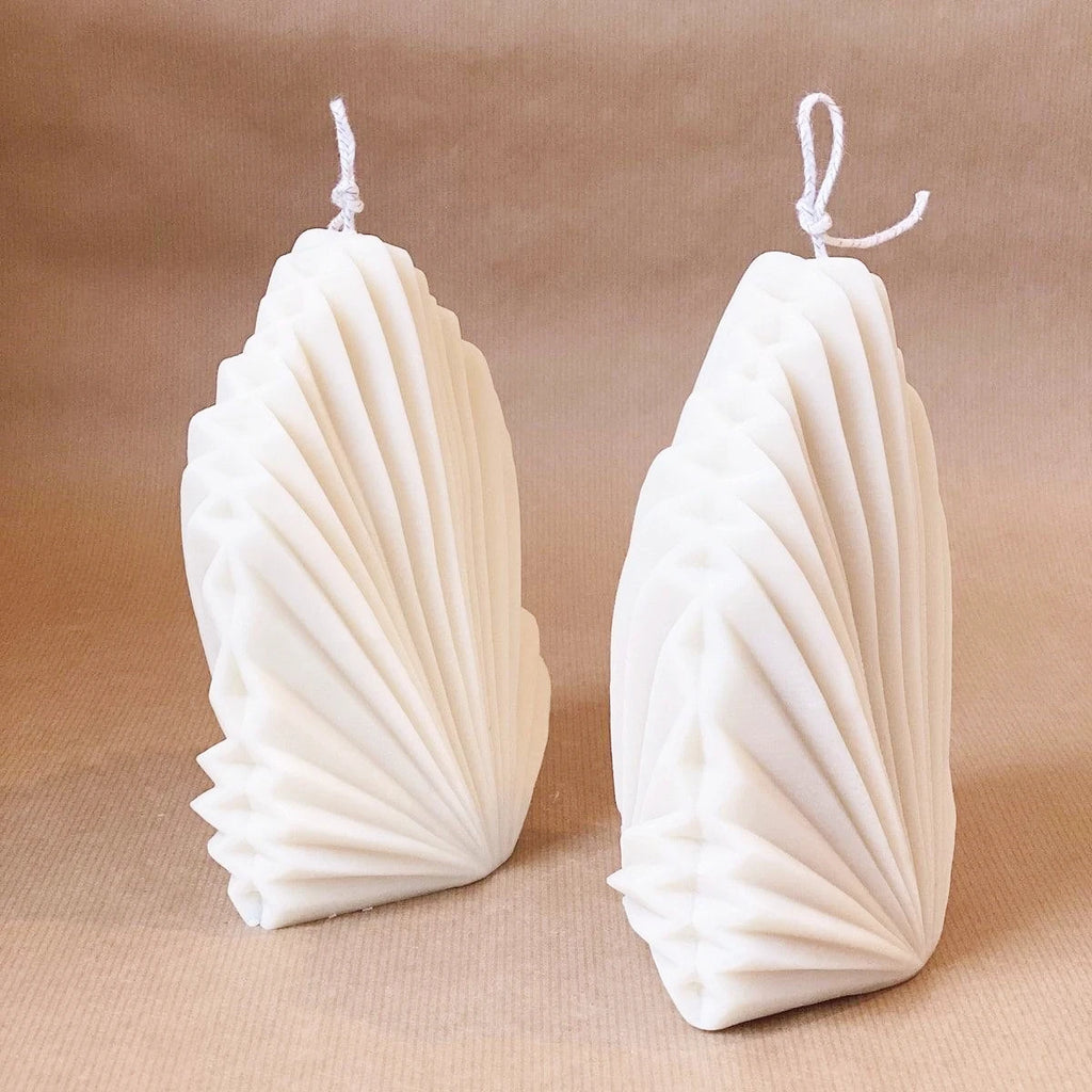 Angled view of two fan-ribbed leaf candle castings showing folded side details