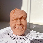 Grinning head casting with raised eyebrows and detailed teeth