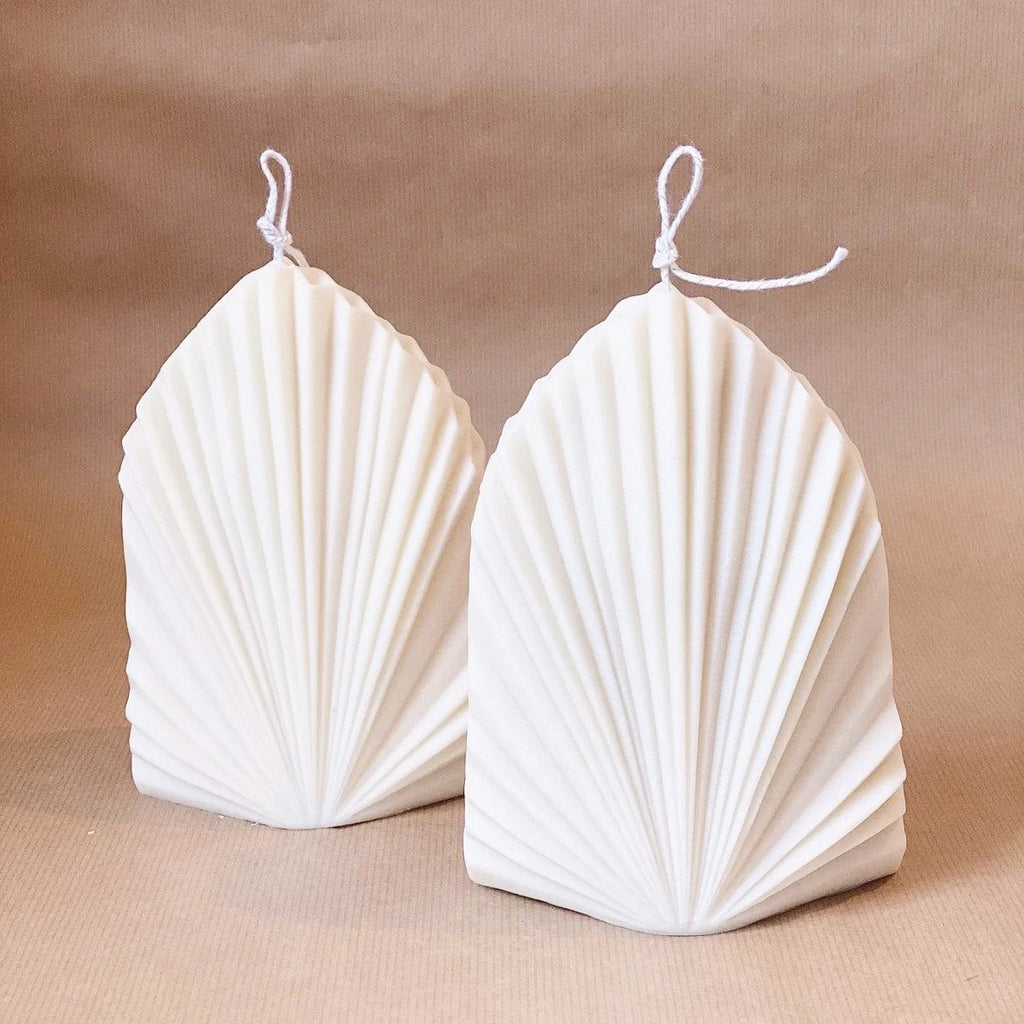 Two white geometric fan-pattern candles with pointed tops