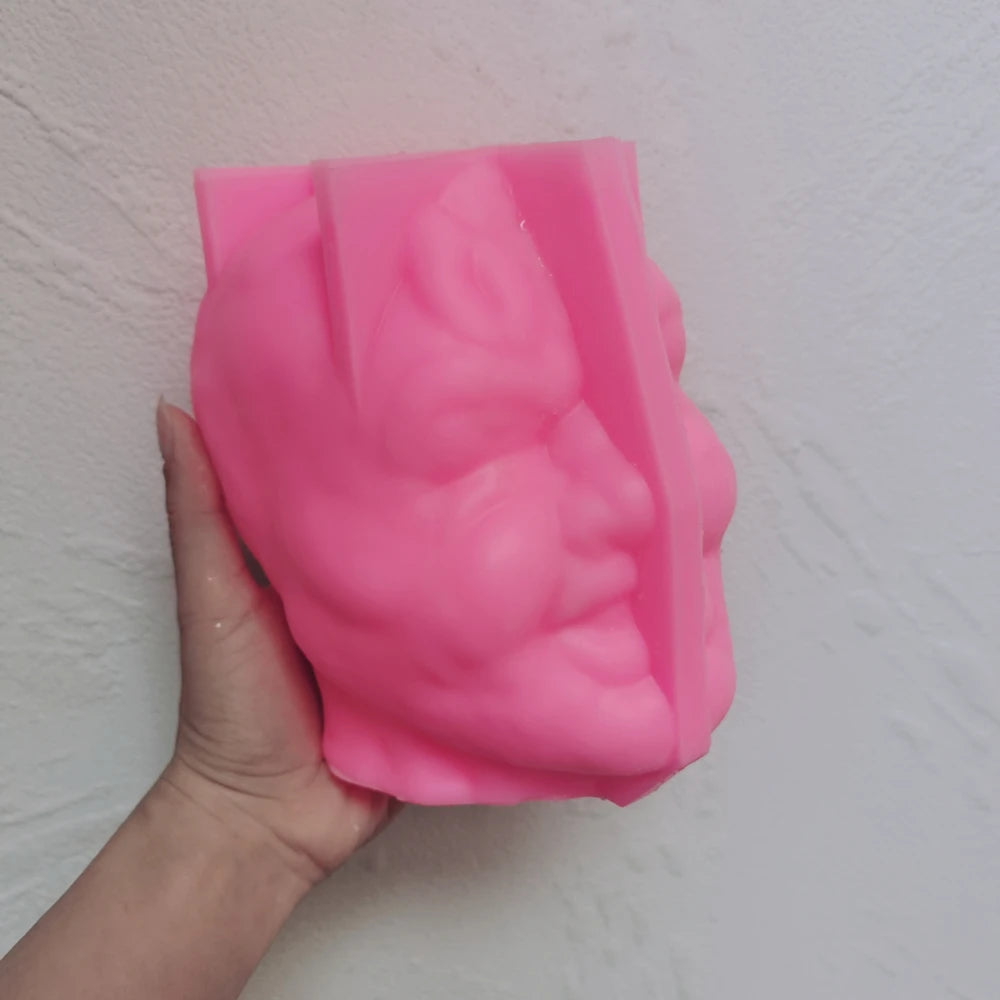 Pink grinning-head silicone mold held in one hand