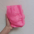 Pink grinning-head silicone mold held in one hand