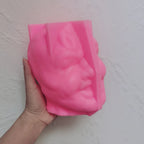 Pink grinning-head silicone mold held in one hand