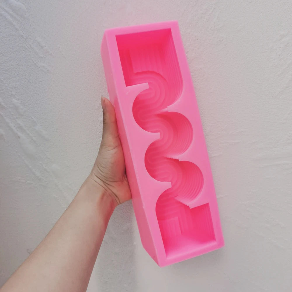 Pink silicone serpentine pillar mold held in a hand