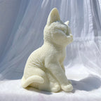Side view of cream cat with curling tail and seated paws