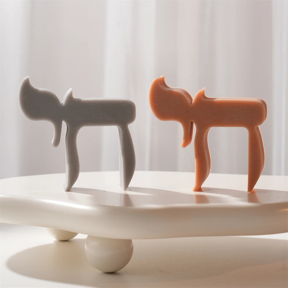 Gray and terracotta Chai-letter candle forms viewed from the side