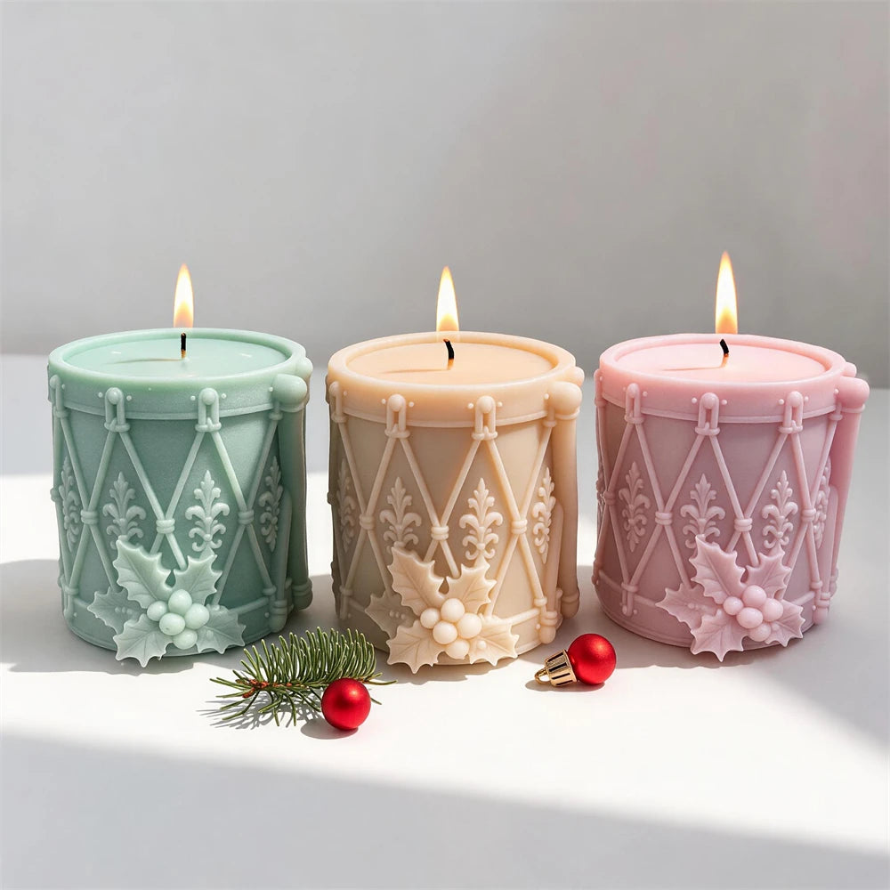 Front view of drum candles with holly leaves and berries near bases