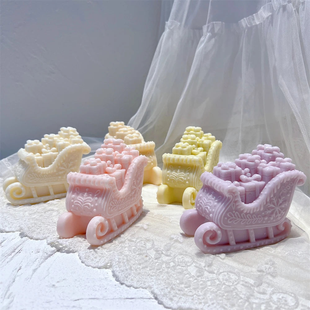 Pastel Christmas gift sleigh candles arranged on a white textile surface