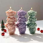 Pink purple and green candles formed from three stacked Highland cow heads