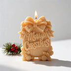 Close view of yellow Merry Christmas candle with bow and floral border