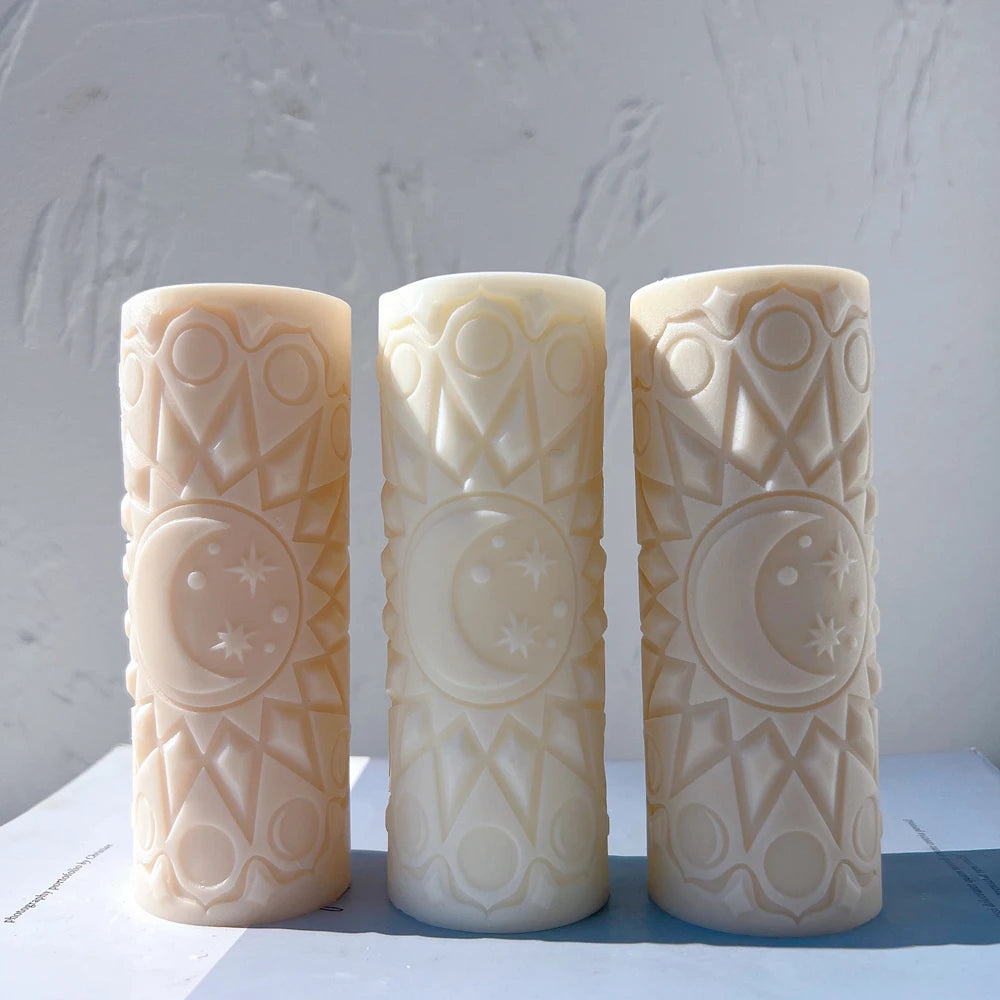 Three cylindrical candles with crescent moon medallions and geometric relief