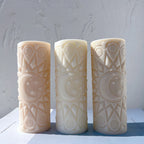 Three cylindrical candles with crescent moon medallions and geometric relief