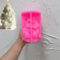 Pink bell-and-bow pinecone silicone mold held in one hand