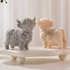 Two standing Highland cow figures with neck bows