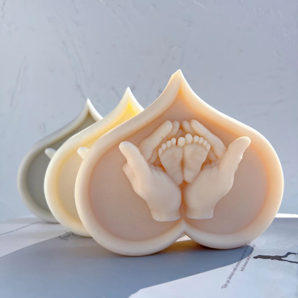 Heart-shaped castings with adult hands cradling small baby feet