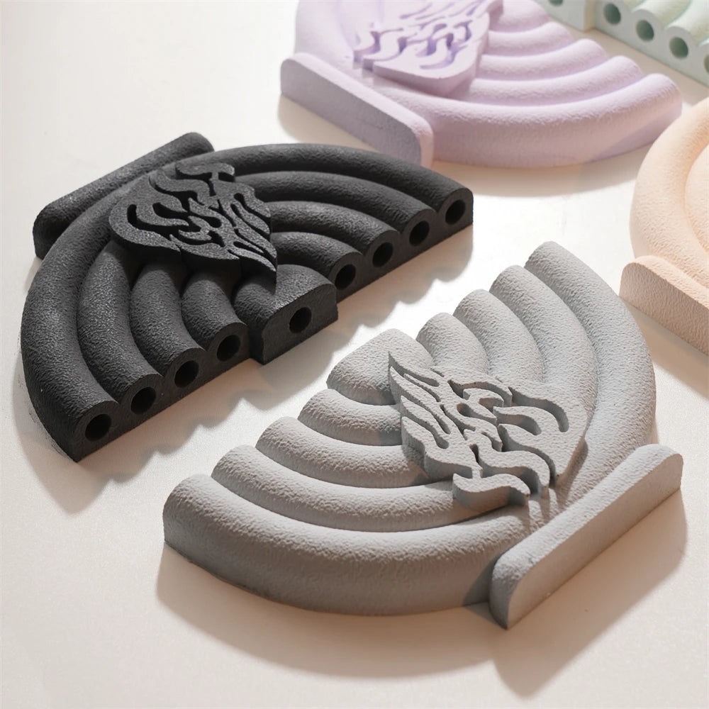 Black and gray nine-branched menorah castings on a flat surface