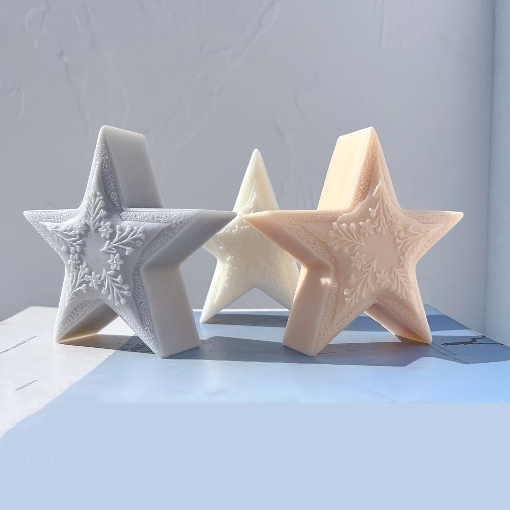 Three textured five-point star candle samples in gray, cream and peach