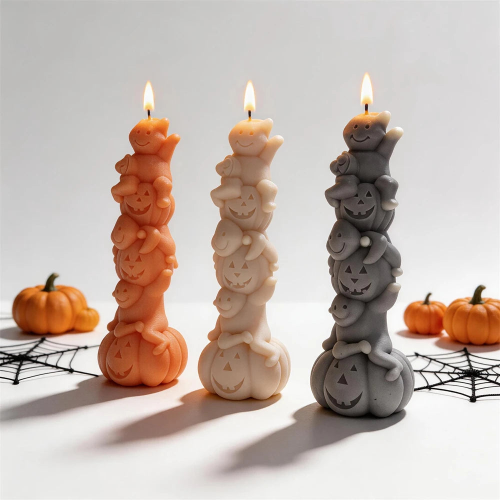 Stacked ghost and pumpkin candles in orange, cream and gray