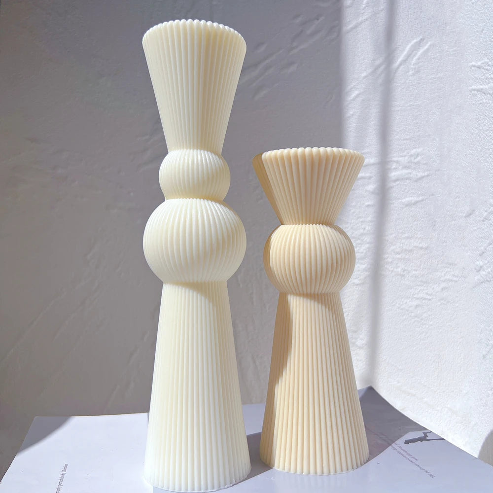 Two ribbed sculptural candle forms with single and double sphere centers