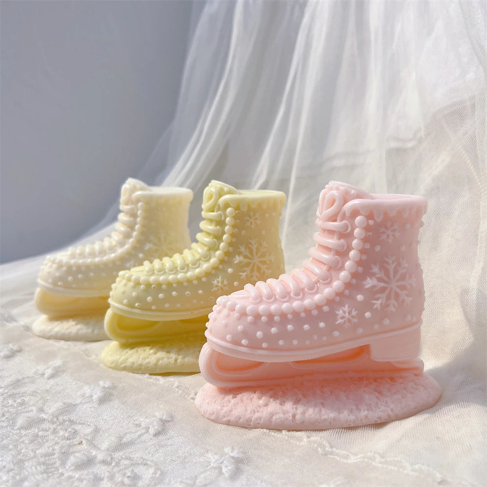 Three ivory yellow and pink ice skate boot candles showing laces and blades