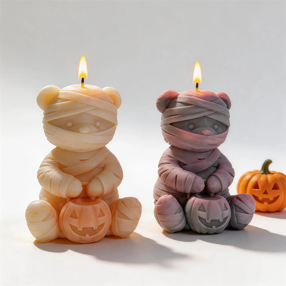 Cream and gray mummy bear candles beside Halloween props