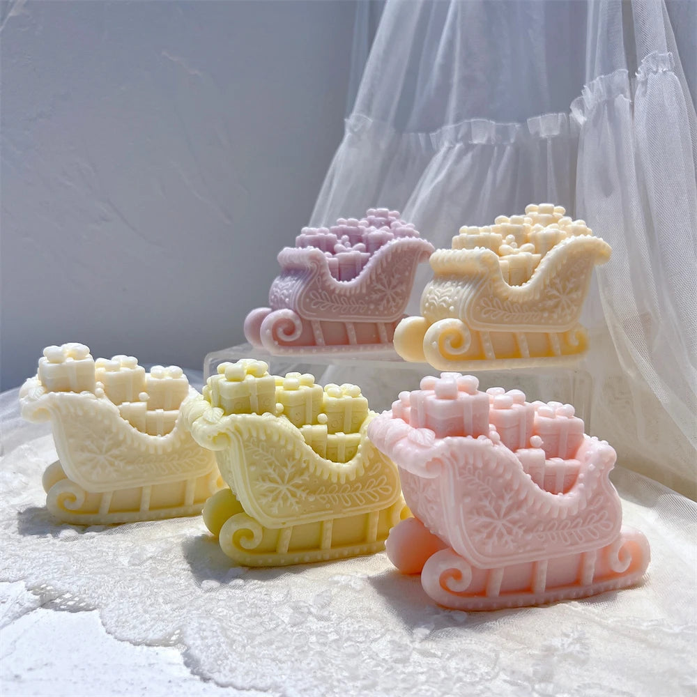 Cream pink and yellow Christmas sleigh candles with ornate curled runners