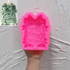 Pink silicone Merry Christmas wreath sign mold held in a hand