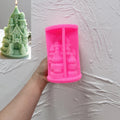 Pink silicone castle mold held in a hand beside a green finished candle