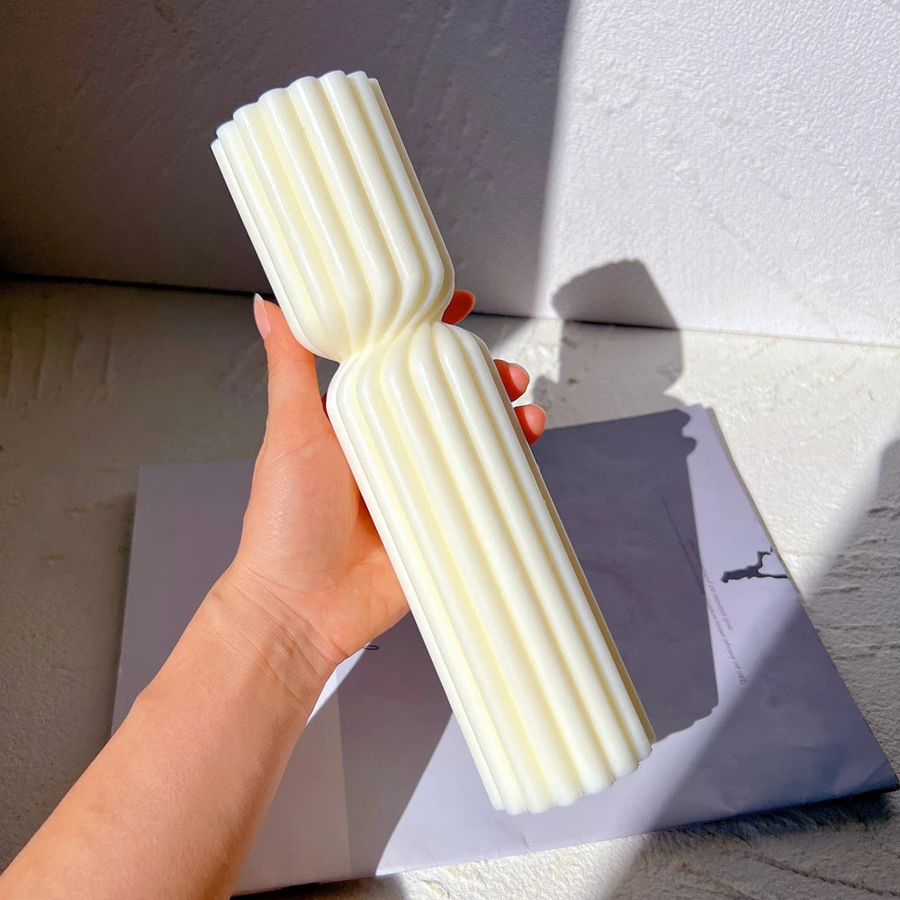 Tall fluted geometric candle being held upright in a hand
