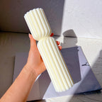 Tall fluted geometric candle being held upright in a hand