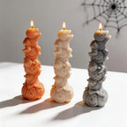 Three ghost pumpkin stack candles beside cobweb decorations