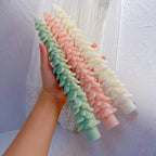 Hand holding three long tree-shaped candles