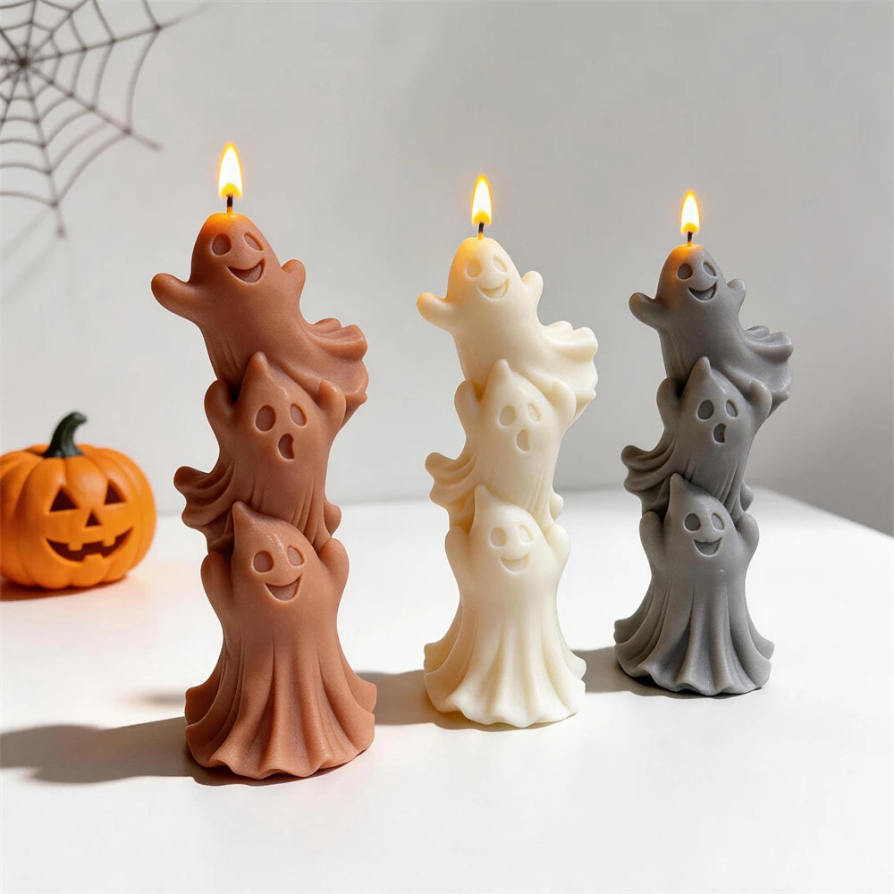 Three ghost stacks beside decorative Halloween pumpkins
