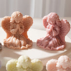Two gentle-faced praying angels in pink and gray wax