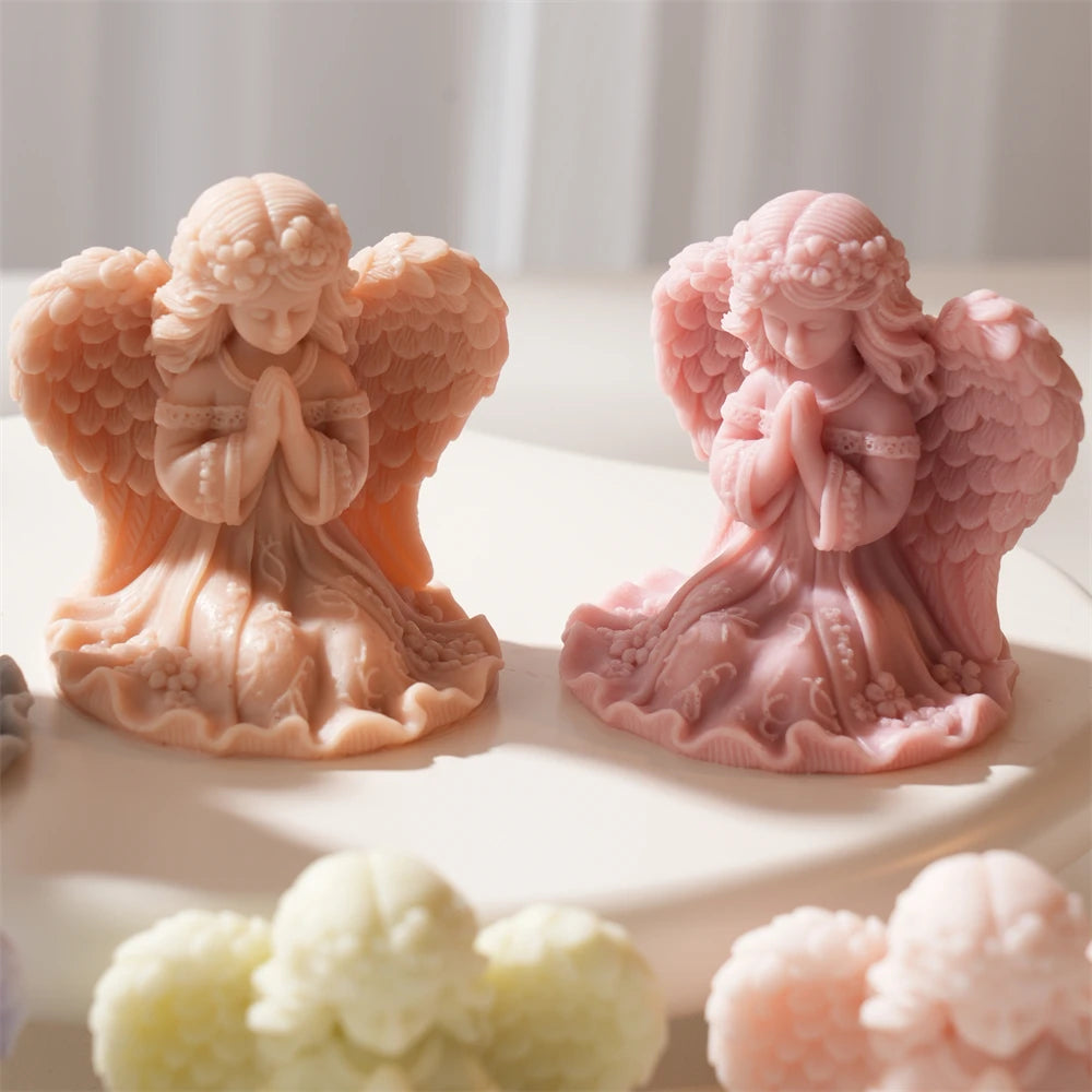 Two gentle-faced praying angels in pink and gray wax